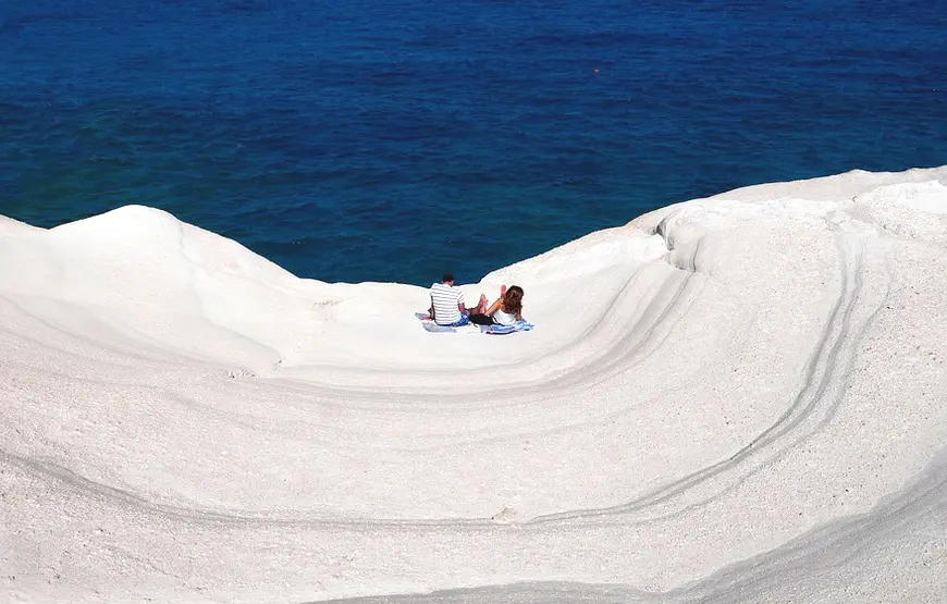 sarakiniko-una-spiaggia-di-marmo-bianco-a-onde-dove-sono-una-coppia-a-prendere-il-sole-sotto-ancora-mare-turchese